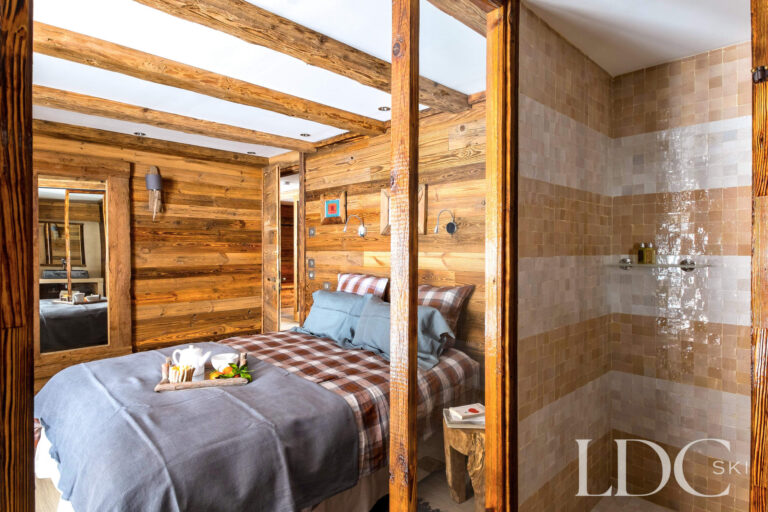 Double bedroom with warm timber interiors and en-suite shower at Le Chalet
