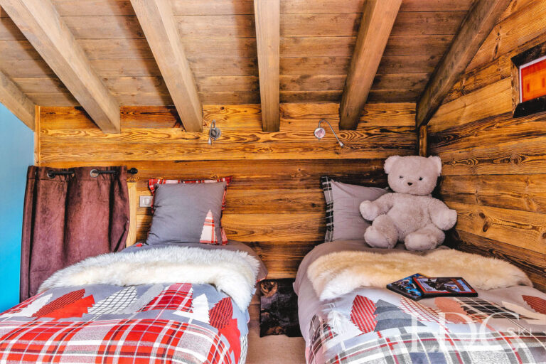 Cosy twin bedroom with traditional wooden walls at Le Chalet
