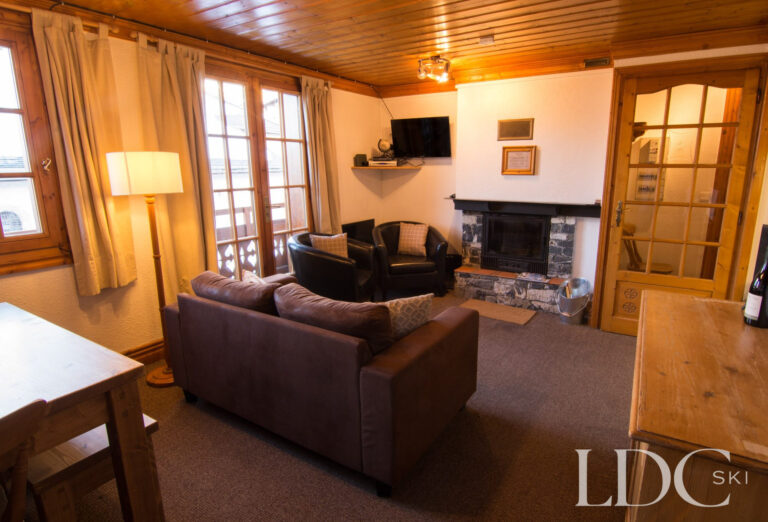 Cosy lounge with fireplace, dining area and balcony doors at Marguerite in St Martin de Belleville