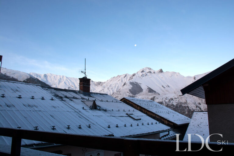 View across snowy rooftops towards the mountains from Marguerite in St Martin de Belleville