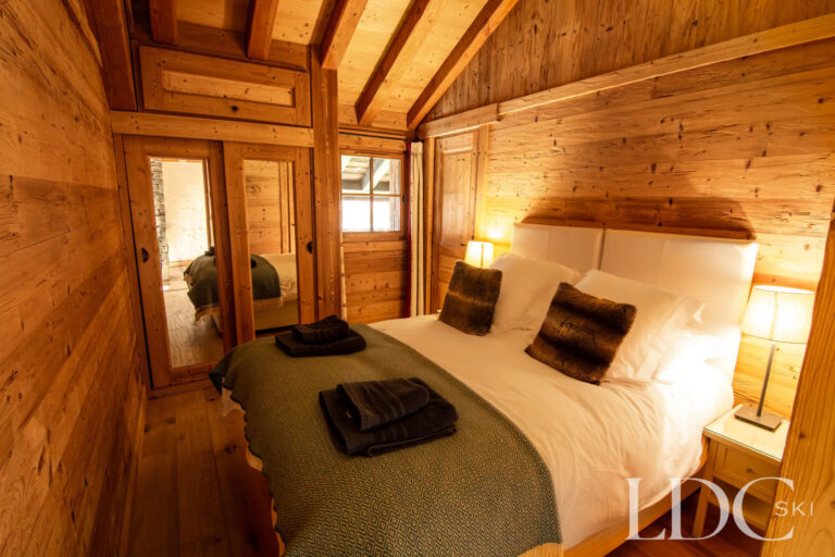 Cosy double bedroom with timber walls and exposed beams at Nant Giraud