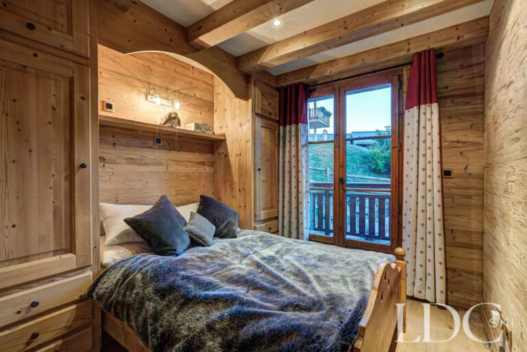 Wood-panelled double bedroom opening onto a balcony at Nant Giraud