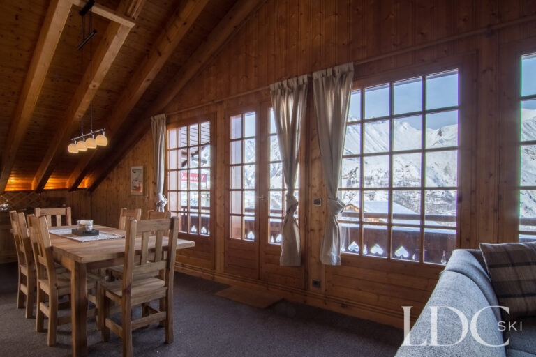 Timber-framed dining room with large windows and snowy views at Perce Neige in St Martin de Belleville