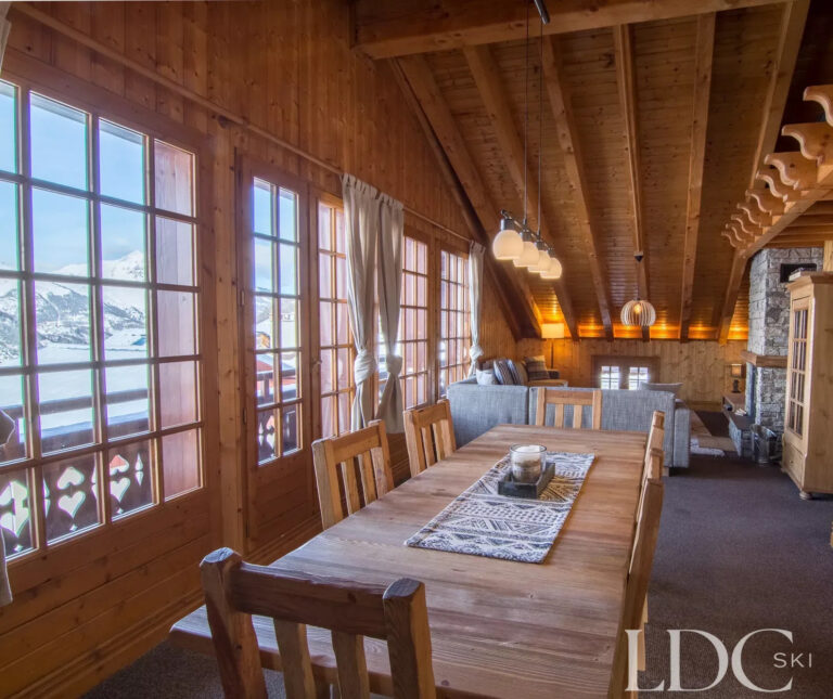 Dining room with large windows overlooking the snowy village and mountains at Perce Neige