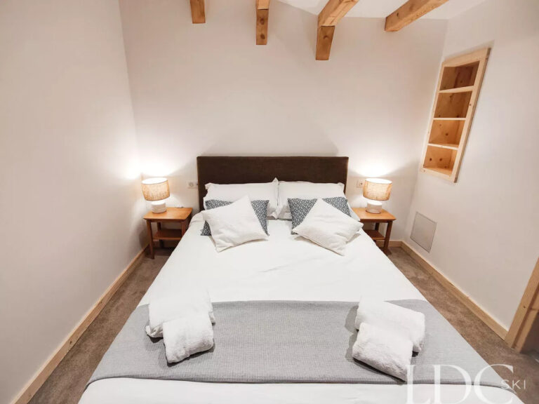 Double bedroom beneath exposed timber beams at Perce Neige in St Martin de Belleville