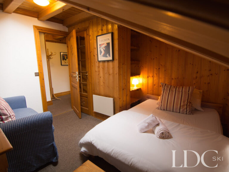 Bright double bedroom with exposed wooden beams at Perce Neige