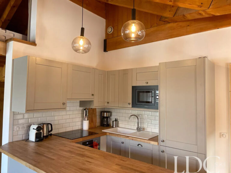 Bright kitchen with timber worktops and exposed beams at Perce Neige