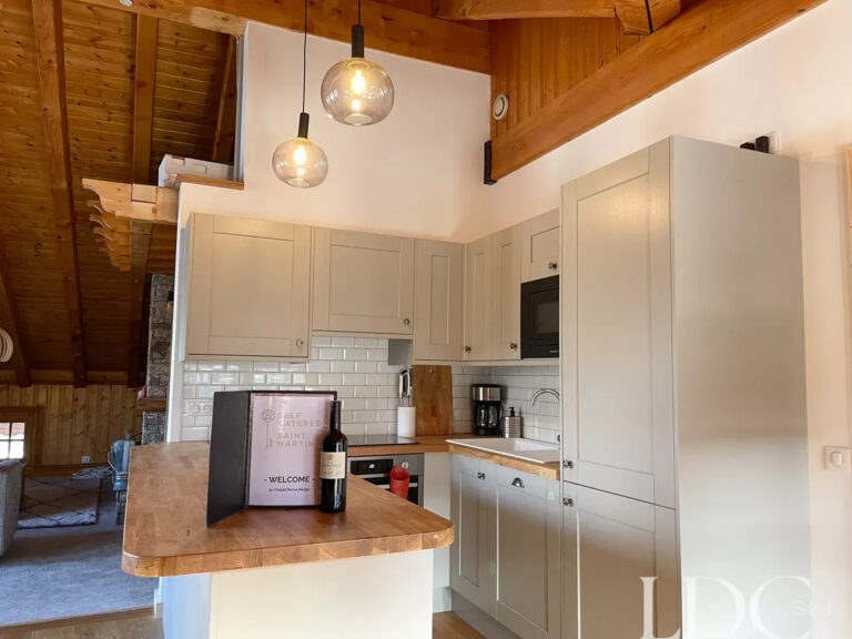 Open-plan kitchen and dining area beneath exposed timber beams at Perce Neige