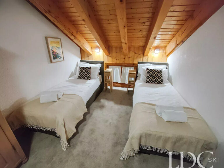 Twin bedroom beneath a sloping timber ceiling at Perce Neige