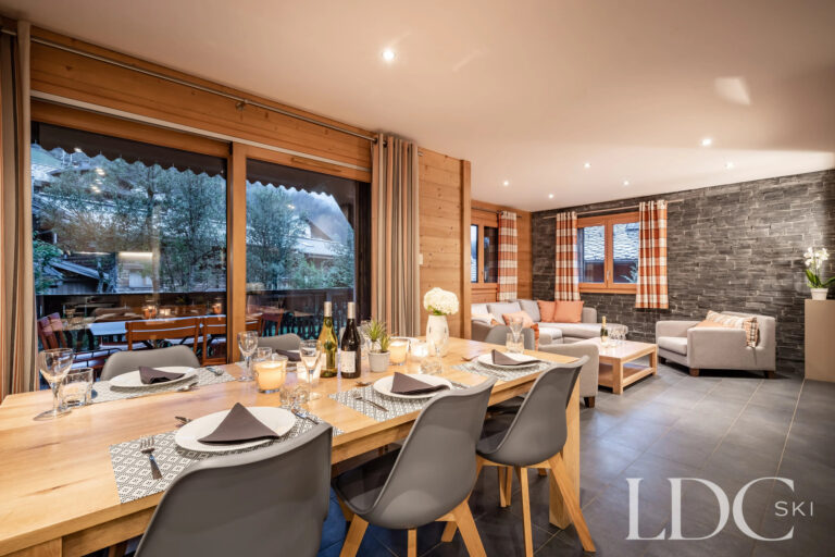 Open plan dining and living area with balcony access at Petit Sapin