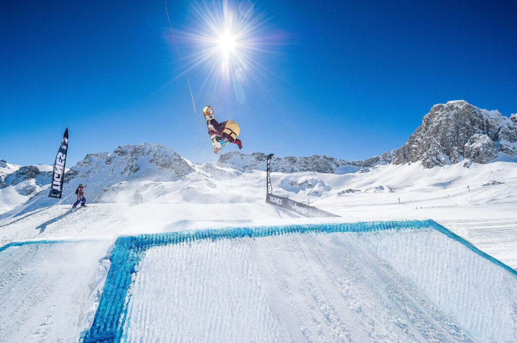 Skier taking on a snowpark feature beneath blue skies in Tignes. © Andy Parant