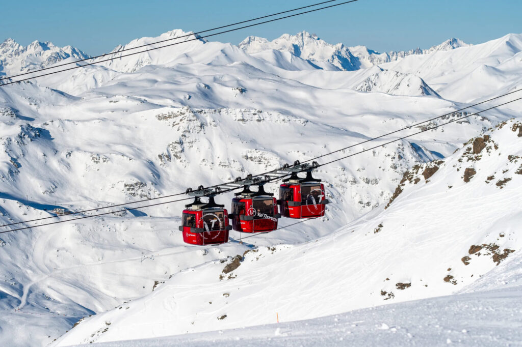 Red lift cabins crossing the snowy mountain landscape above Val Thorens. © T. Loubere – OT Val Thorens